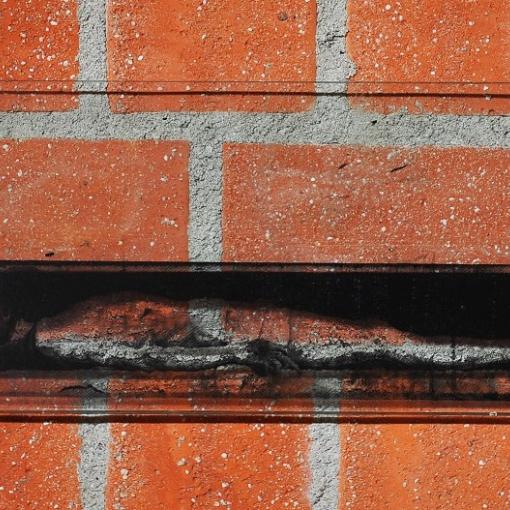 Querformatige Glasplatte mit Siebdruck des toten Christus vor roter Backsteinwand