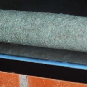 Filzrolle mit herausragendem Stahlstück, in Wandvitrine eingelassen