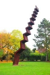Vertikale, schlanke, angeschrägte Stufenskulptur im Grünen