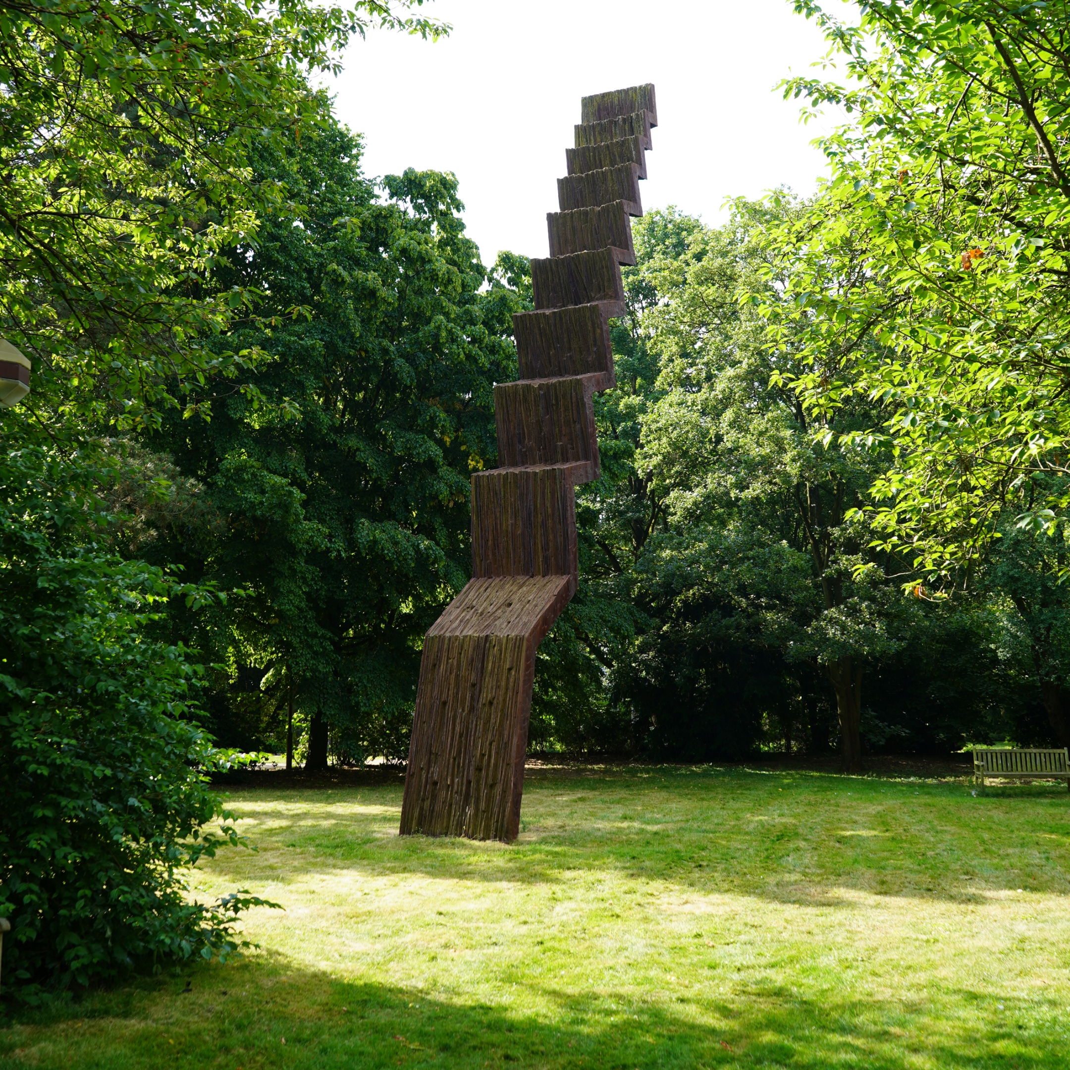 Vertikale, schlanke, angeschrägte Stufenskulptur im Grünen