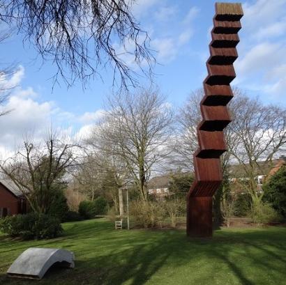 Vertikale, schlanke, angeschrägte Stufenskulptur im Grünen