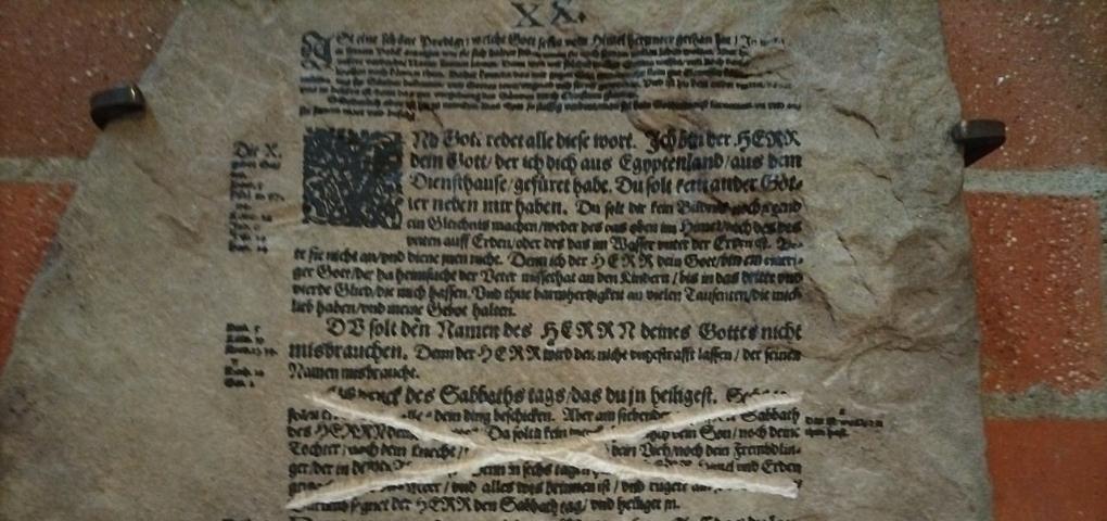 Steintafel mit Zehn-Gebote-Text aus der Lutherbibel, eine Passage durchgestrichen