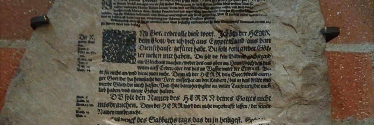 Steintafel mit Zehn-Gebote-Text aus der Lutherbibel, eine Passage durchgestrichen