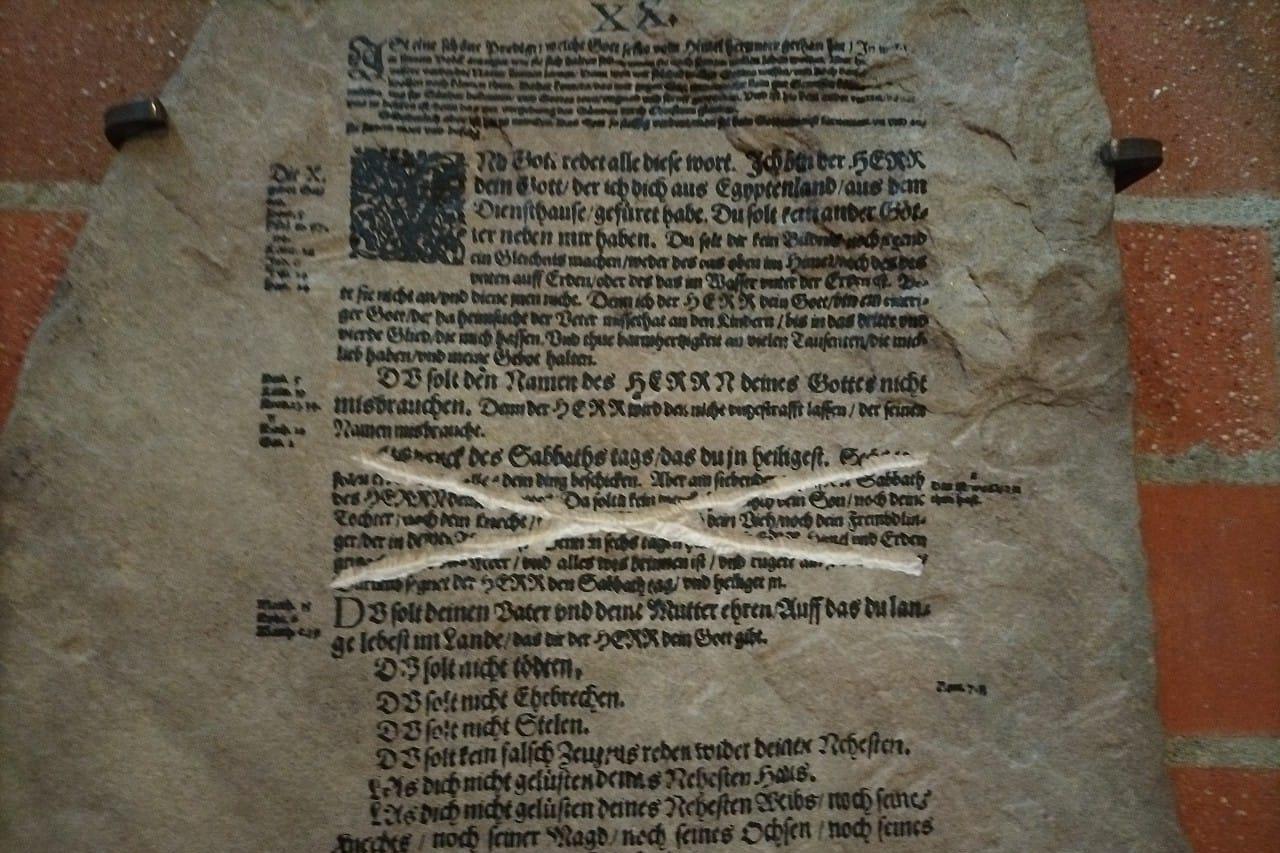 Steintafel mit Zehn-Gebote-Text aus der Lutherbibel, eine Passage durchgestrichen