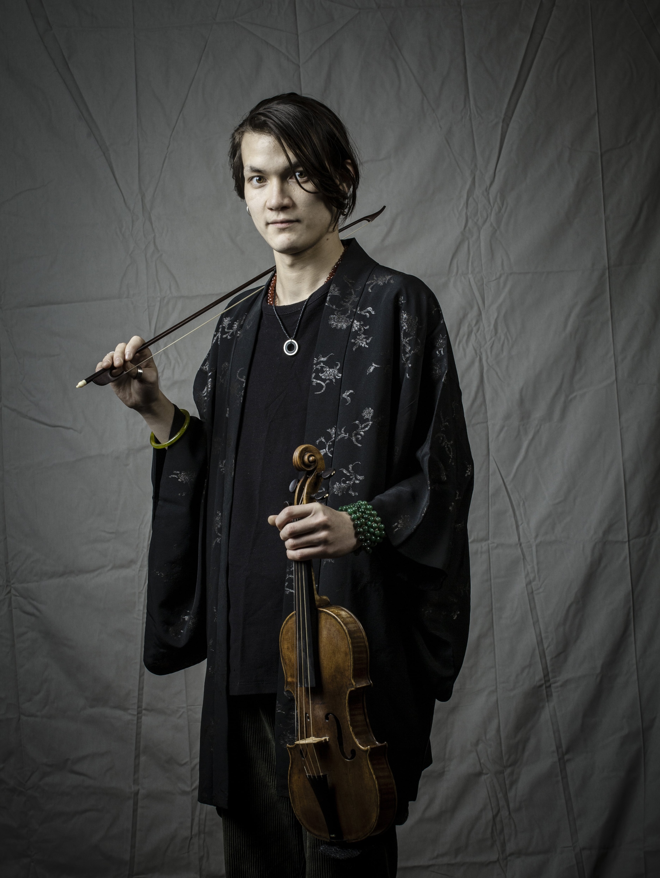 Künstler hält in der linken Hand eine Violine, mit der rechten Hand streicht er mit dem Bogen am Hals entlang